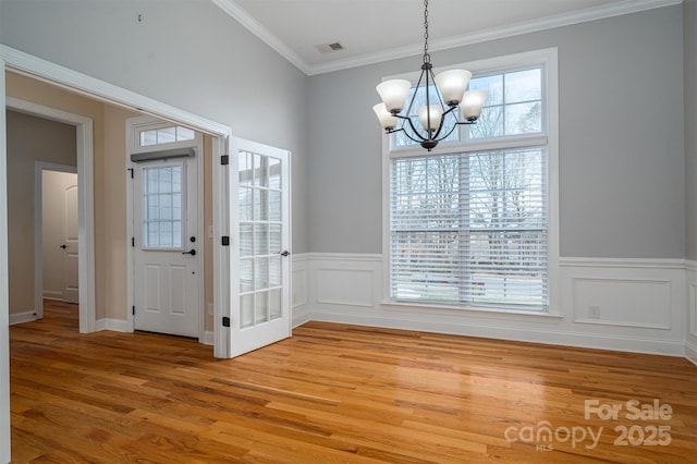 unfurnished dining area featuring crown molding, hardwood / wood-style floors, and a chandelier