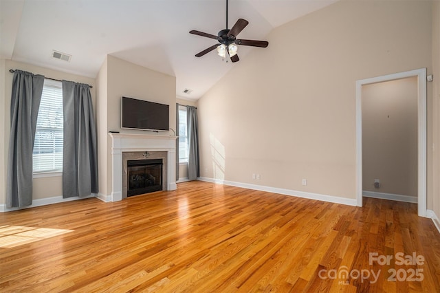 unfurnished living room featuring light hardwood / wood-style flooring, high vaulted ceiling, ceiling fan, and plenty of natural light