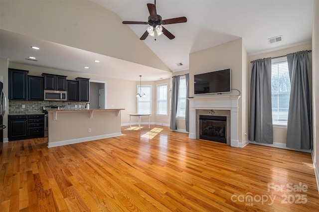 unfurnished living room featuring ceiling fan, high vaulted ceiling, and light hardwood / wood-style floors