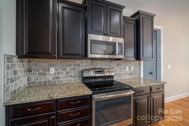 kitchen with stainless steel appliances, tasteful backsplash, light stone counters, and light hardwood / wood-style floors