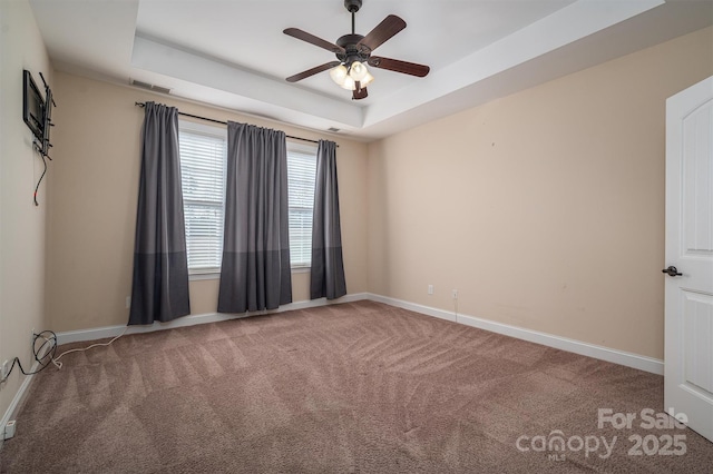 carpeted empty room with ceiling fan and a tray ceiling