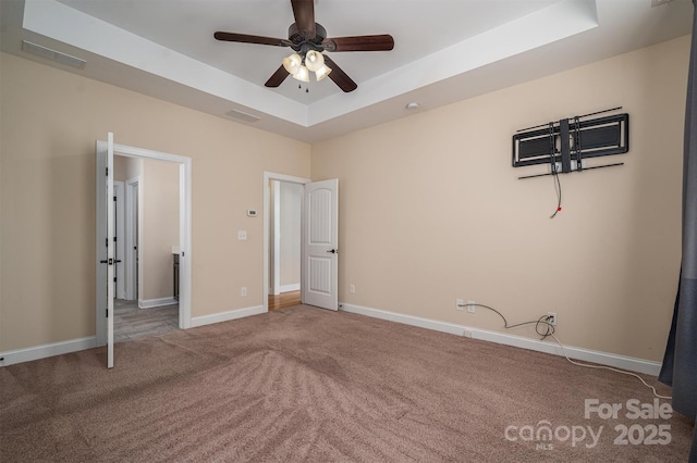 unfurnished bedroom with a tray ceiling, ceiling fan, and carpet