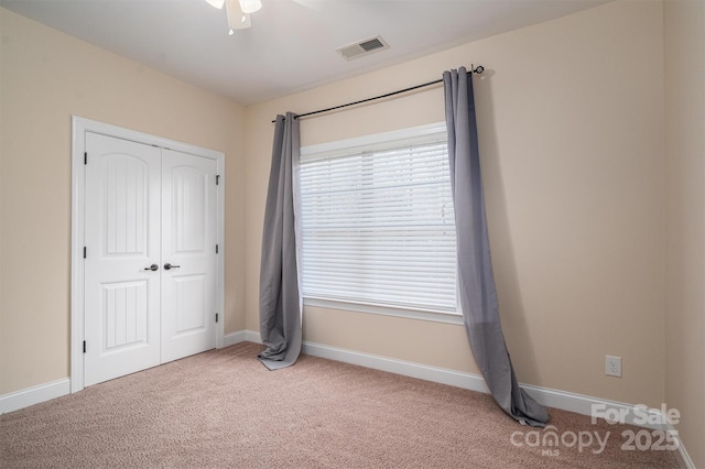 unfurnished bedroom featuring light colored carpet, a closet, and ceiling fan