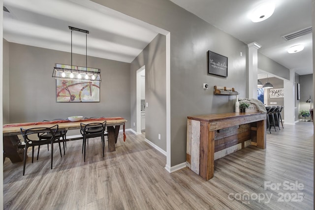 dining area with ornate columns and hardwood / wood-style floors