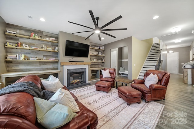 living room featuring ceiling fan, a high end fireplace, and light hardwood / wood-style floors