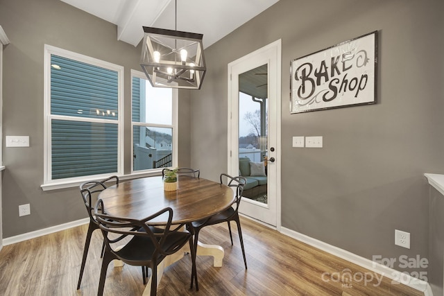 dining room featuring hardwood / wood-style flooring, beam ceiling, and a chandelier