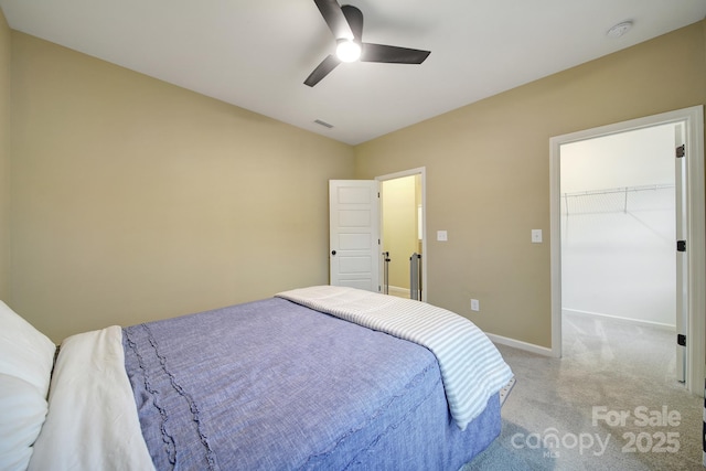 bedroom with ceiling fan, light colored carpet, and a spacious closet