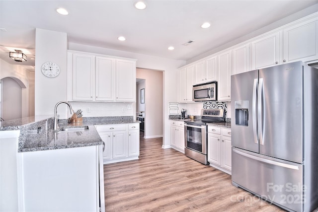 kitchen featuring sink, light hardwood / wood-style flooring, white cabinetry, stainless steel appliances, and kitchen peninsula