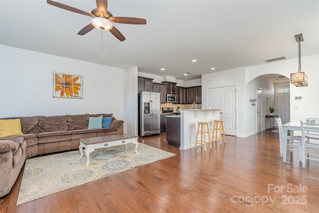 living room with dark hardwood / wood-style flooring and ceiling fan