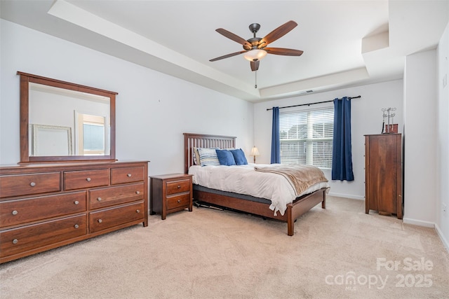 carpeted bedroom with ceiling fan and a raised ceiling