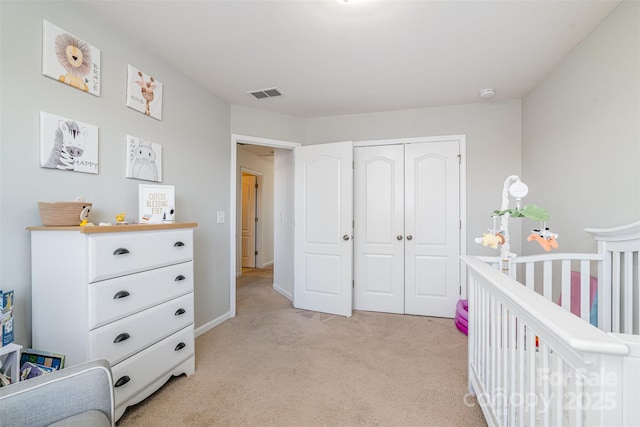 bedroom featuring a nursery area, light carpet, and a closet