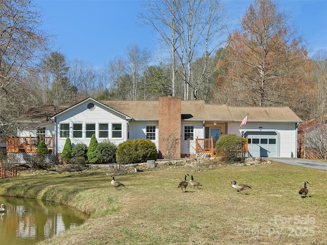 ranch-style home with driveway, a garage, a chimney, and a front lawn