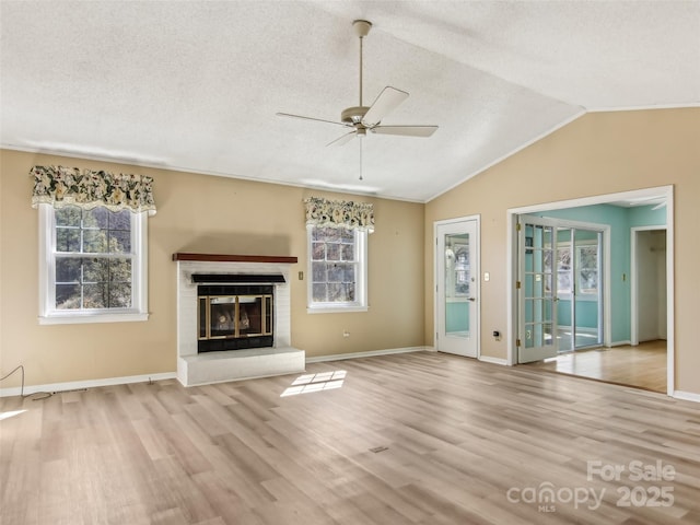 unfurnished living room featuring vaulted ceiling, a textured ceiling, a fireplace, and wood finished floors