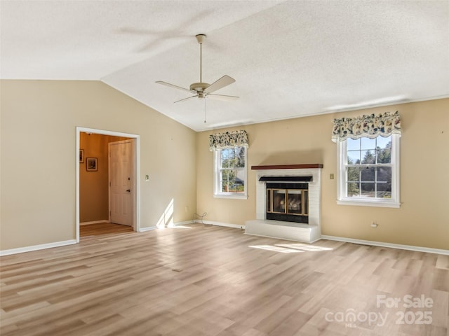 unfurnished living room with light wood-type flooring, a fireplace, lofted ceiling, and a textured ceiling