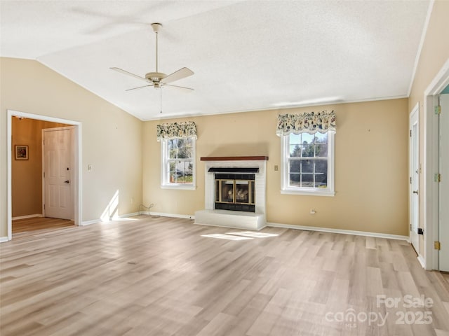 unfurnished living room featuring vaulted ceiling, ceiling fan, light wood finished floors, and a fireplace