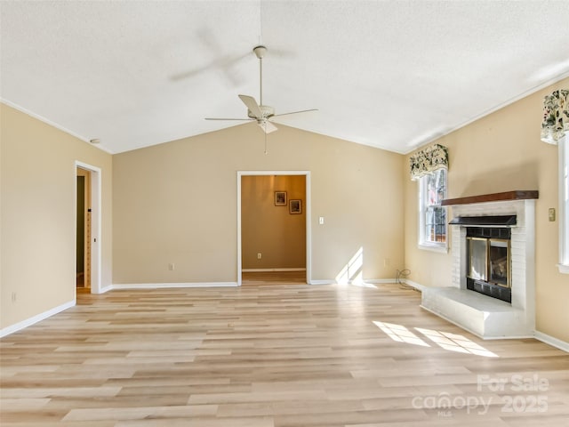 unfurnished living room featuring vaulted ceiling, a textured ceiling, a brick fireplace, and light wood-style floors