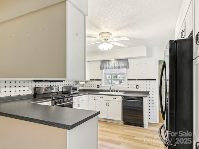 kitchen featuring dark countertops, white cabinets, a sink, a peninsula, and black appliances