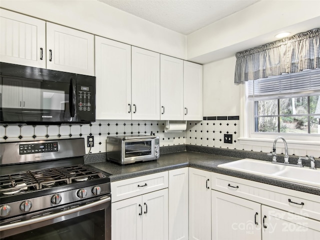 kitchen with a toaster, white cabinetry, stainless steel gas stove, a sink, and black microwave