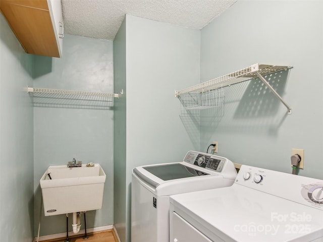 washroom featuring a textured ceiling, laundry area, independent washer and dryer, and a sink