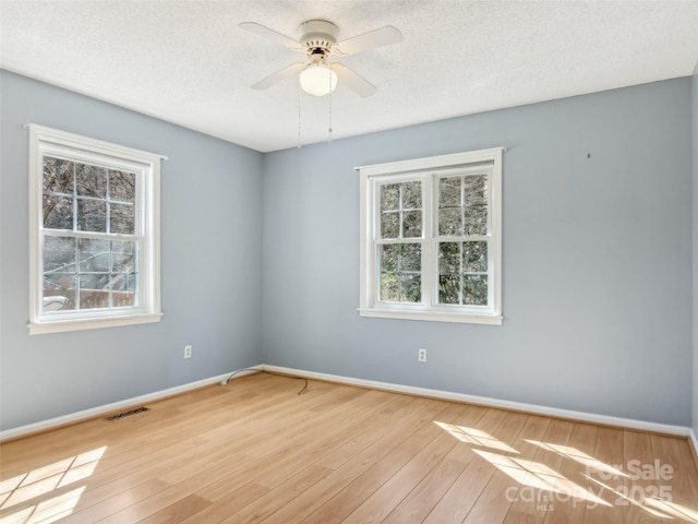 unfurnished room featuring ceiling fan, a textured ceiling, baseboards, and wood finished floors