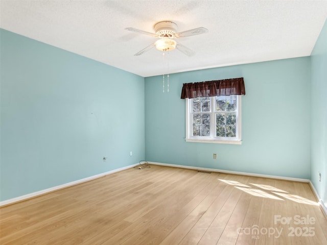 unfurnished room featuring baseboards, visible vents, ceiling fan, wood finished floors, and a textured ceiling