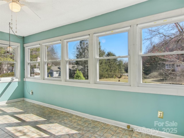 unfurnished sunroom with ceiling fan