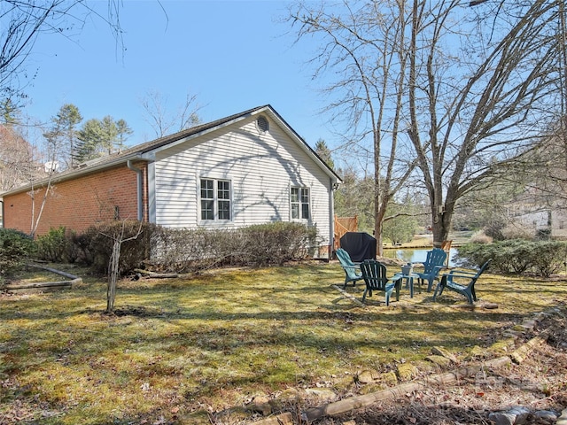 view of home's exterior featuring a yard, a fire pit, and brick siding