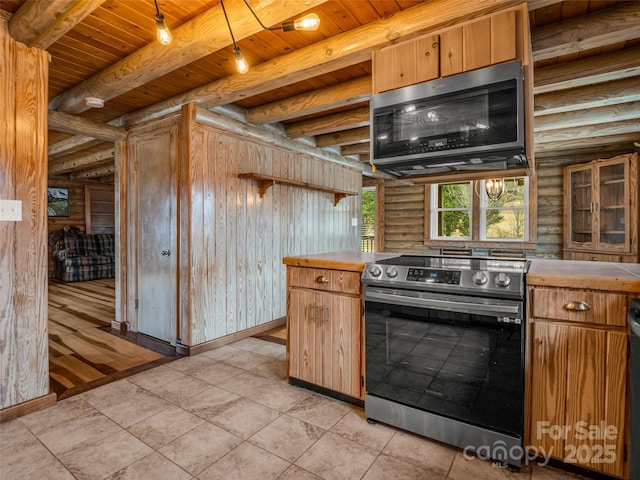 kitchen with light tile patterned flooring, beam ceiling, wooden ceiling, appliances with stainless steel finishes, and log walls