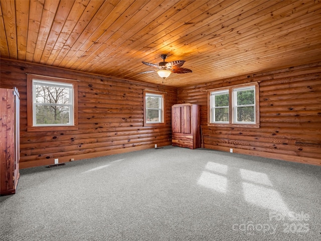 carpeted spare room with a wealth of natural light, rustic walls, and wood ceiling