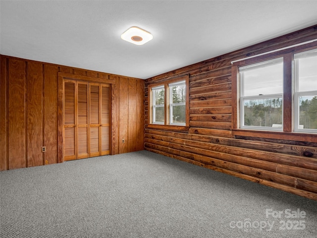 unfurnished room with rustic walls and carpet flooring