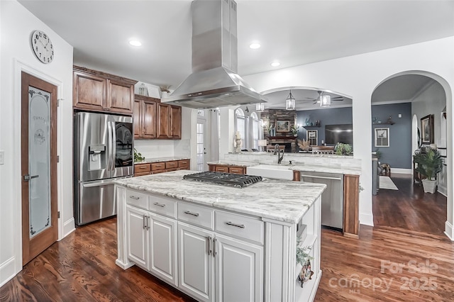 kitchen featuring appliances with stainless steel finishes, white cabinetry, sink, island exhaust hood, and a center island