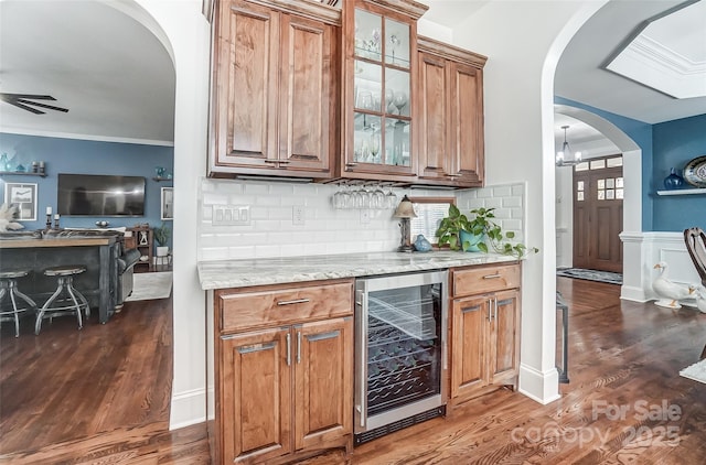 bar with wine cooler, dark hardwood / wood-style flooring, ceiling fan, light stone countertops, and decorative backsplash