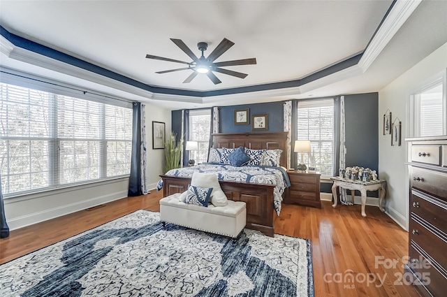 bedroom featuring a raised ceiling, ornamental molding, ceiling fan, and light hardwood / wood-style flooring