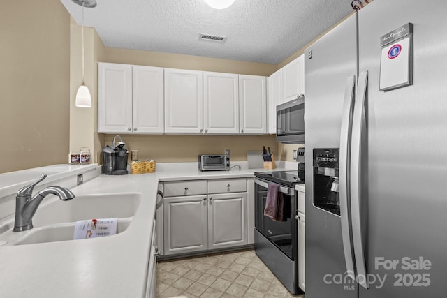 kitchen featuring sink, decorative light fixtures, white cabinets, and appliances with stainless steel finishes