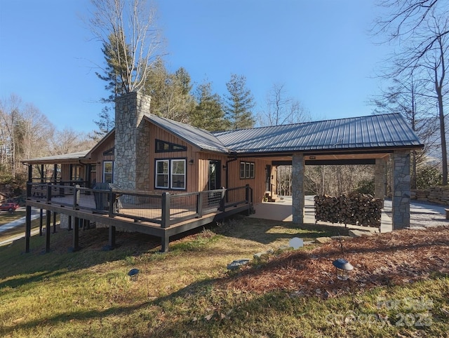 back of property featuring a yard, metal roof, a chimney, and a wooden deck