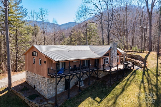 rear view of property featuring crawl space, a chimney, metal roof, and a lawn