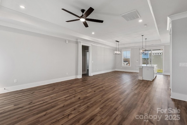 unfurnished living room featuring dark hardwood / wood-style flooring, sink, ceiling fan with notable chandelier, and a tray ceiling