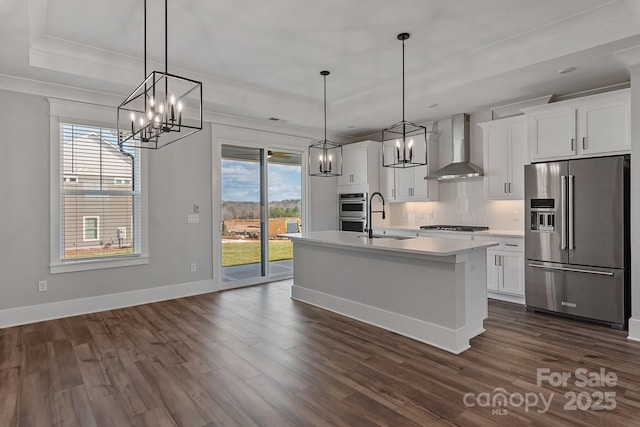 kitchen with pendant lighting, white cabinetry, stainless steel appliances, and wall chimney exhaust hood