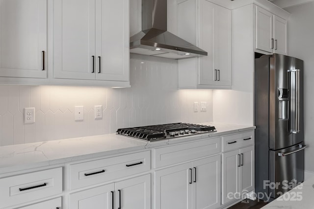 kitchen featuring light stone countertops, white cabinetry, appliances with stainless steel finishes, and wall chimney exhaust hood