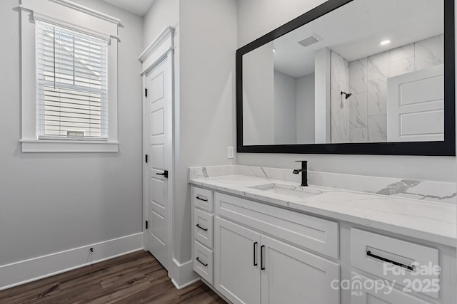 bathroom with hardwood / wood-style flooring, vanity, and a shower