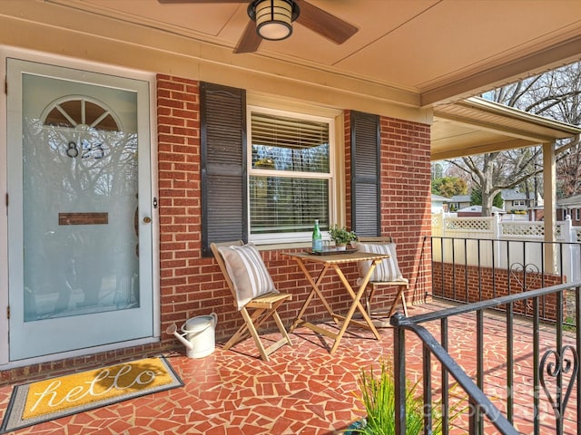 property entrance featuring ceiling fan, brick siding, a porch, and fence