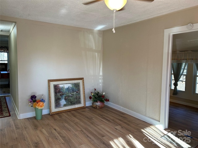 unfurnished room featuring ceiling fan, hardwood / wood-style floors, and a textured ceiling