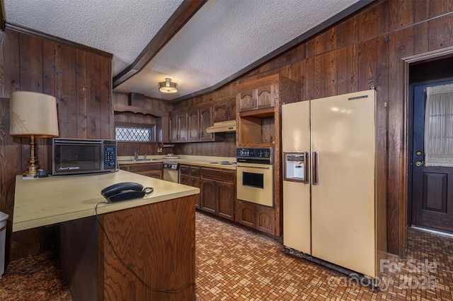 kitchen with stovetop, wall oven, white fridge with ice dispenser, a textured ceiling, and kitchen peninsula