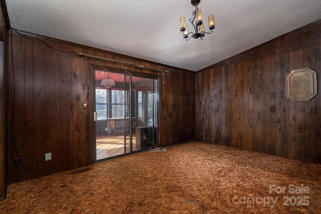 empty room with carpet floors, wooden walls, and a textured ceiling