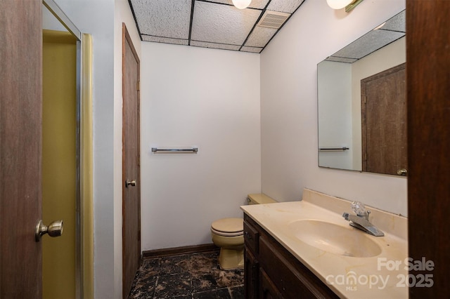 bathroom featuring a drop ceiling, vanity, and toilet