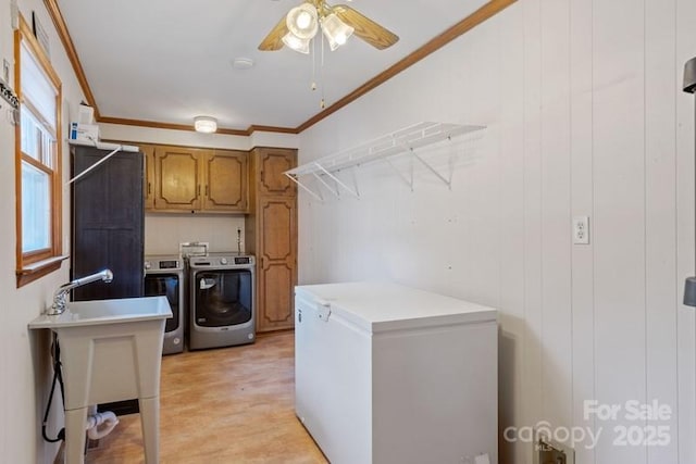 laundry area with sink, crown molding, ceiling fan, cabinets, and washer and dryer