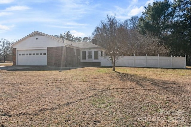 view of front facade featuring a front yard, fence, driveway, and an attached garage