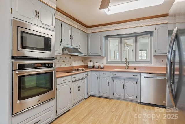 kitchen with sink, crown molding, light hardwood / wood-style flooring, appliances with stainless steel finishes, and gray cabinetry