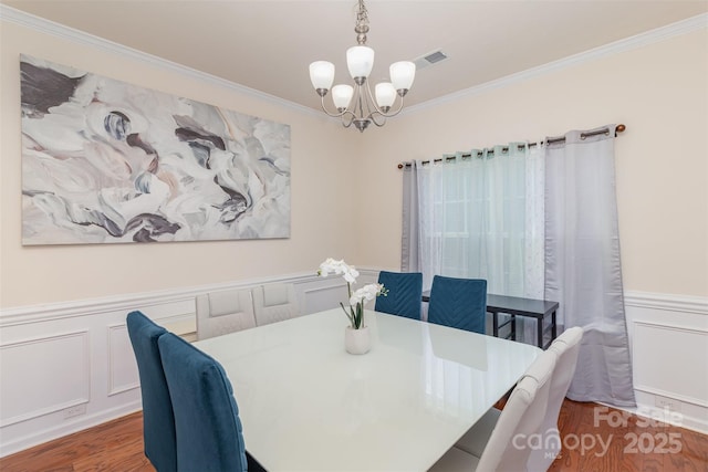 dining area with crown molding, a chandelier, and hardwood / wood-style flooring