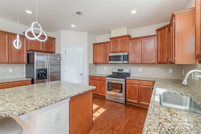 kitchen featuring sink, dark hardwood / wood-style flooring, a kitchen breakfast bar, hanging light fixtures, and stainless steel appliances